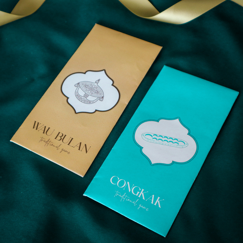 Raya money packets, each adorned with designs inspired by beloved traditional Malay games such as congkak, wau bulan, gasing, and batu seremban